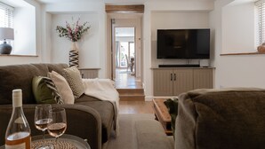 Ein modernes Wohnzimmer mit einer Couch, einem Fernseher und einer Weinflasche.
