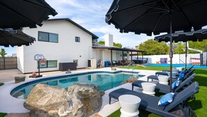 A swimming pool with lounge chairs and umbrellas, a basketball hoop, and a house with a covered patio. - Heated Pool, Hot Tub, Game Room & Sport Court (Glendale)
