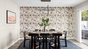 A dining area with a cactus-themed wallpaper, a central vase with flowers, and a modern chandelier. - Heated Pool, Hot Tub, Game Room & Sport Court (Glendale)