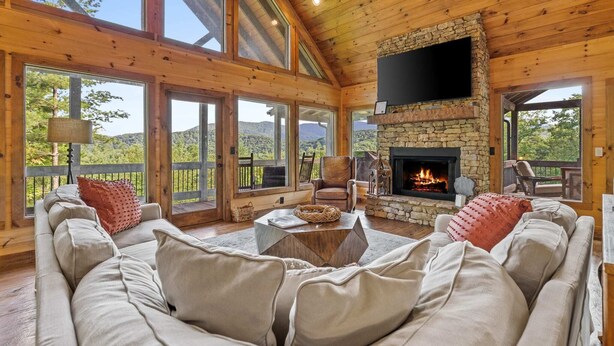 A cozy living room with a stone fireplace, large windows, and a comfortable seating area. - Surreal Views~Outdoor Fireplace Pool Table&Hot Tub (Epworth)