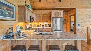 A wooden cabin interior with a kitchen featuring granite countertops, stainless steel appliances, and wooden cabinets. - Surreal Views~Outdoor Fireplace Pool Table&Hot Tub (Epworth)