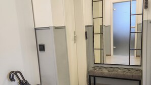 A hallway with a bench, a mirror, and a trash bin. - Geli Homes L1 - 2x Kingsize Bett, 1 bis 4 Pers, Parkplatz, TV, Wifi, Kaffee, Tee (Lünen)