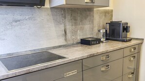 A modern kitchen with a built-in stove, a coffee machine, and a glass of water on the counter. - Geli Homes L1 - 2x Kingsize Bett, 1 bis 4 Pers, Parkplatz, TV, Wifi, Kaffee, Tee (Lünen)