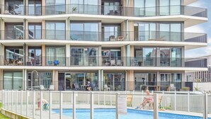 A multi-story hotel with balconies, a swimming pool, and outdoor seating areas.