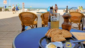 A table with bread, butter, and a bottle of Blanquette de Naumer on a beachside setting.