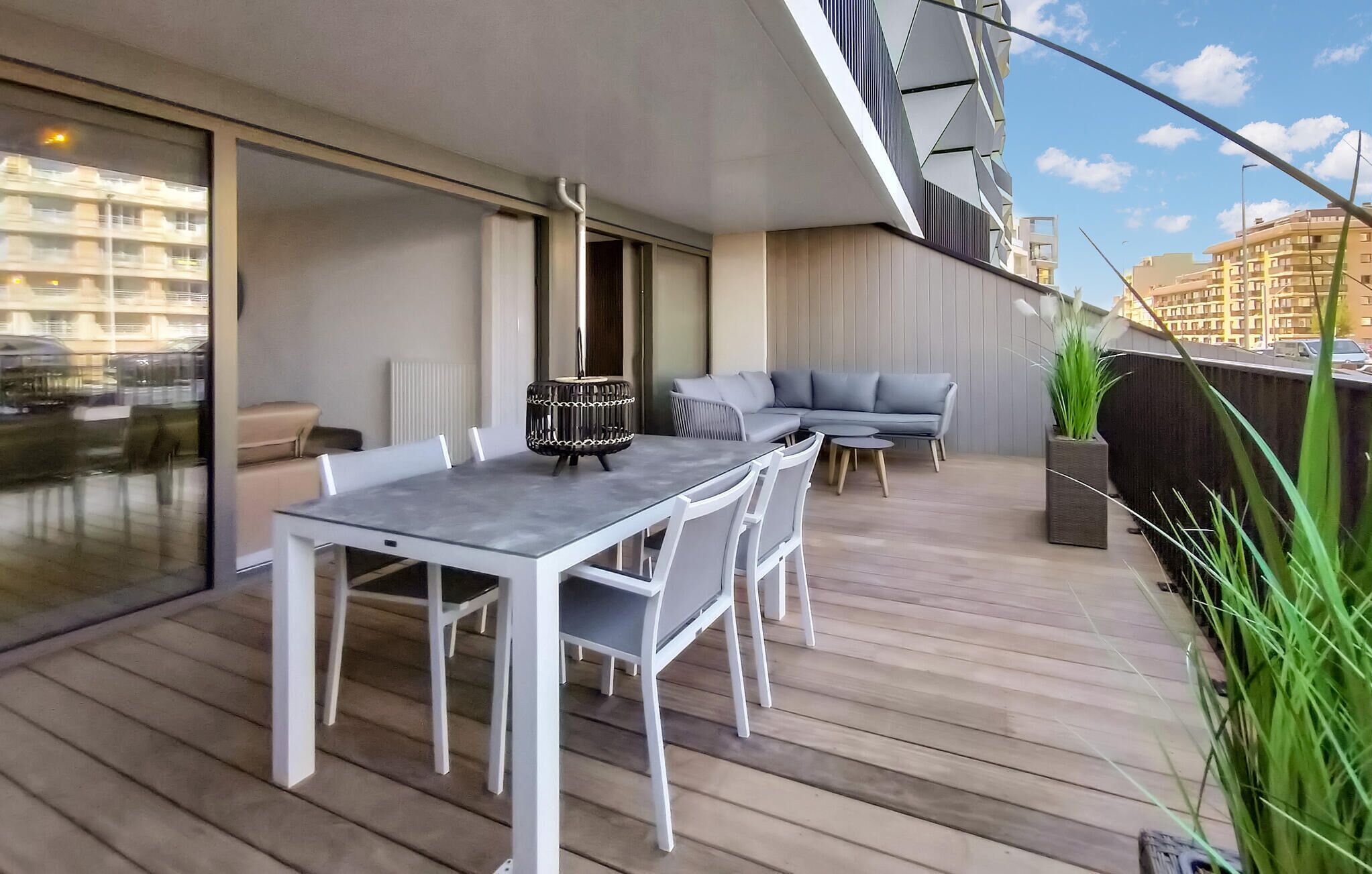 Ein moderner Balkon mit Essplatz, Sitzgruppe, einer Couch und einem Blumentopf.