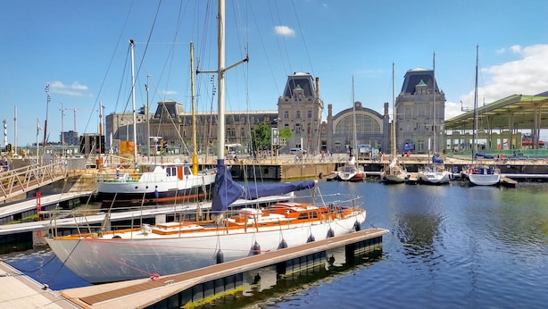 A marina with boats docked, a large building with a clock tower, and a covered walkway.
