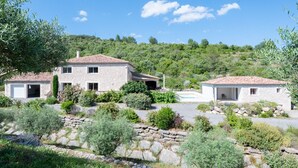 Ein Haus aus Stein mit Ziegeldach, einer Garage und einem Swimmingpool.