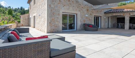 Un edificio de piedra con un patio que incluye un sofá de mimbre y una mesa de comedor.