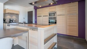 Eine moderne Küche mit Holzausstattung, einer zentralen Kochinsel und integrierten Geräten.