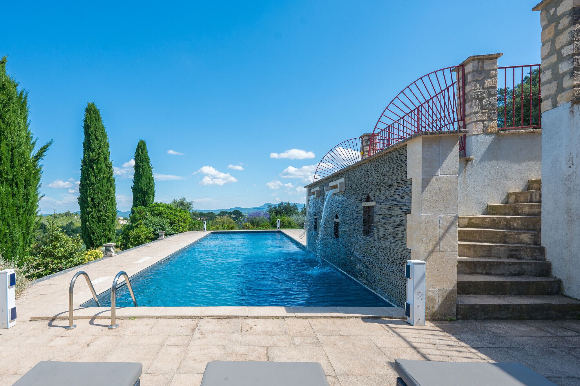 Ein Swimmingpool mit Steinmauer und roter Geländer.