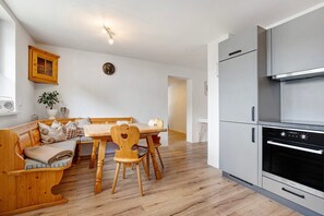 Une cuisine moderne dotée d’un four encastré et d’un coin repas avec des meubles en bois.