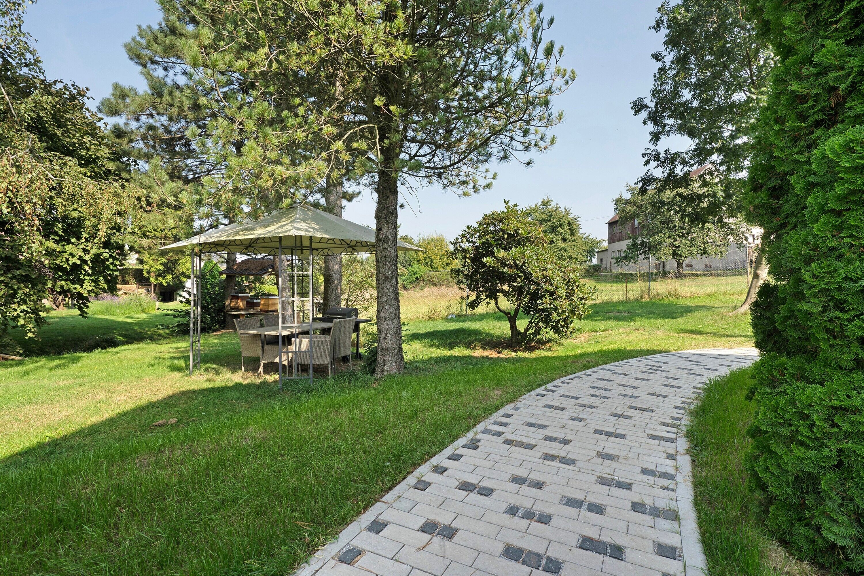 A paved pathway, a gazebo, and surrounding greenery.