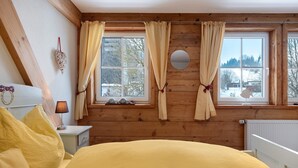 A room with wooden walls, a bed with yellow bedding, a nightstand with a lamp, and a window with curtains. - 'Doppelzimmer Ohne Balkon 26' with Shared Garden and Wi-Fi (St. Georgen)