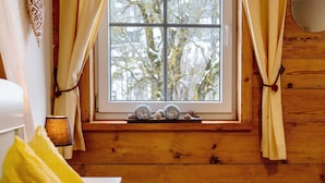 A wooden cabin interior with a window, curtains, a lamp, and decorative items on the sill. - 'Doppelzimmer Ohne Balkon 26' with Shared Garden and Wi-Fi (St. Georgen)