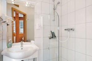 Un bagno con lavandino, specchio, doccia e una porta in legno.