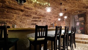 Un interior rústico con paredes de ladrillo visto, taburetes de madera y lámparas colgantes.