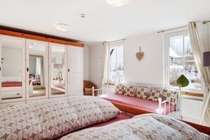 Une chambre à coucher avec un lit, une fenêtre avec des rideaux, un radiateur et un miroir.
