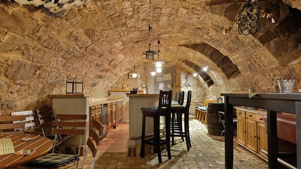 Un interior rústico de piedra con barra, muebles de madera y techo de piedra.