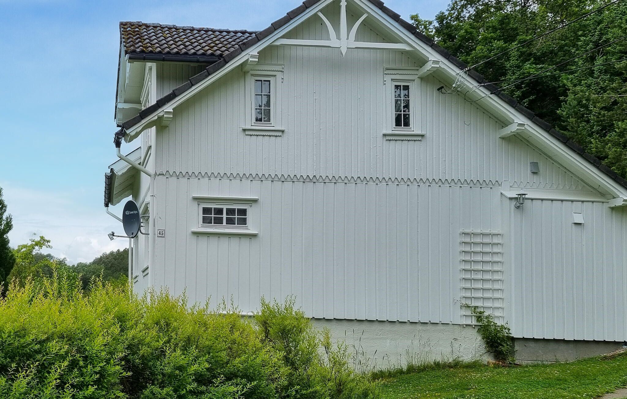 Ein weißes Gebäude mit Satteldach, zahlreichen Fenstern und einer Satellitenschüssel.
