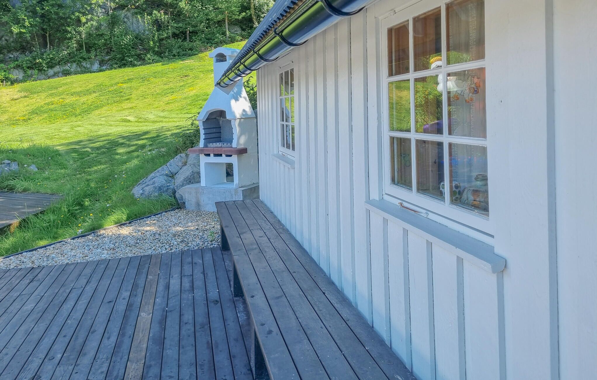 A wooden deck leading to a white building with a chimney and windows.