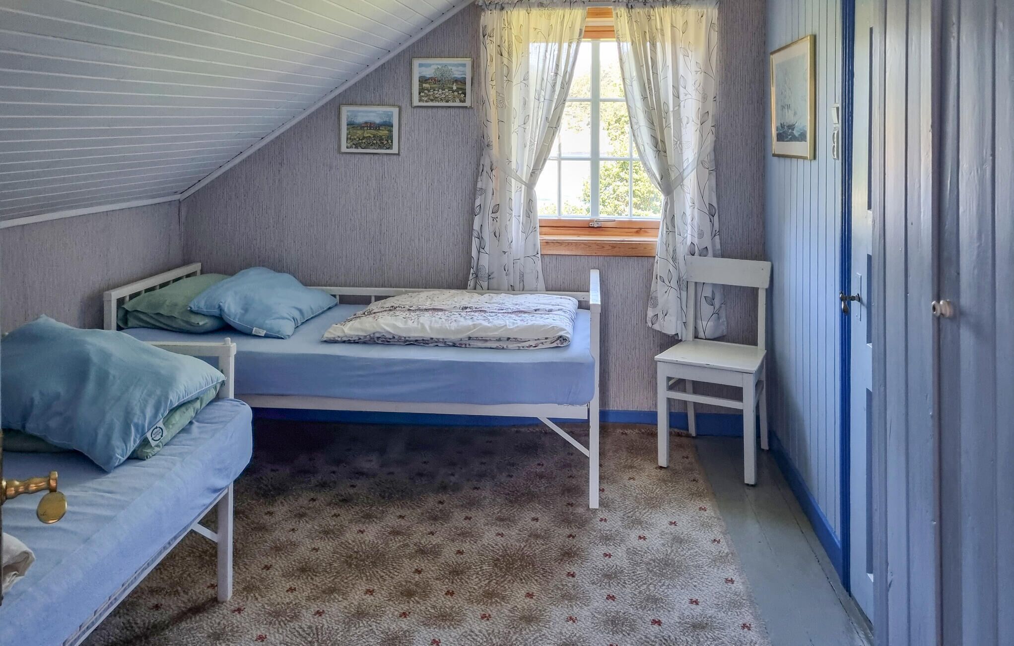 Une chambre avec un lit superposé, un lit simple, une chaise, une fenêtre avec des rideaux et une porte.