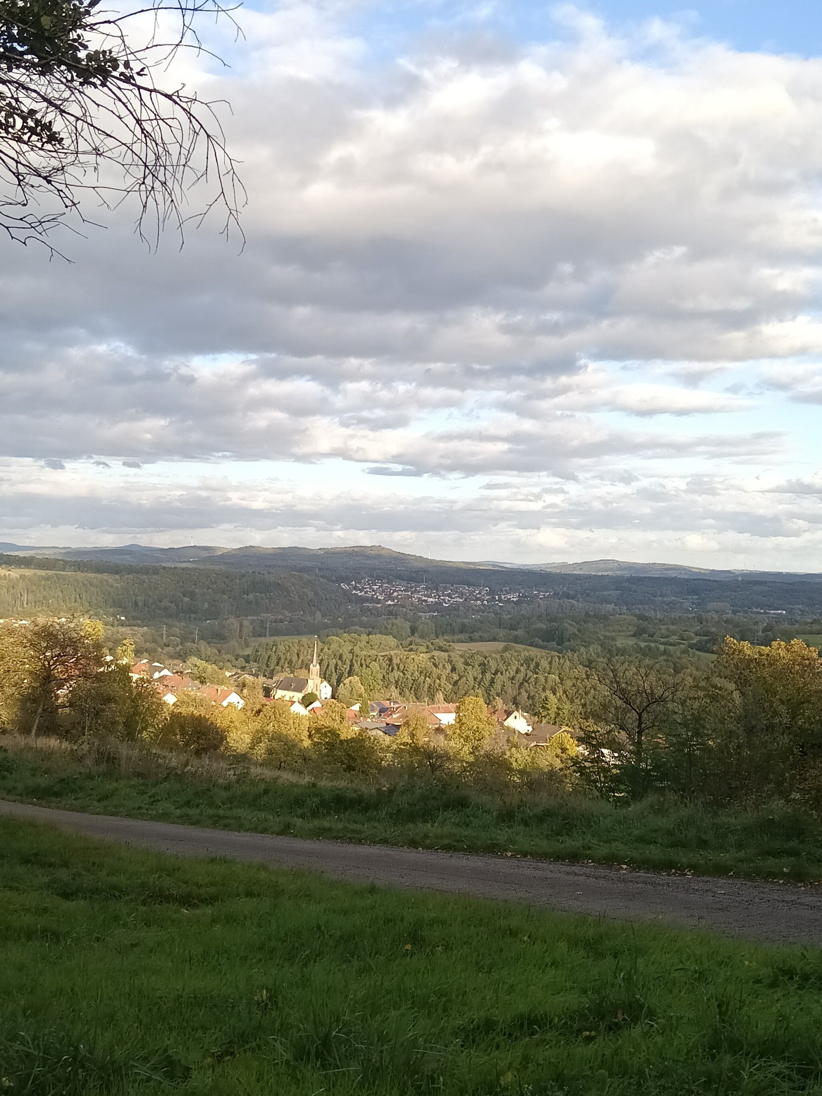 Un paisaje rural con un pequeño pueblo, una iglesia y una carretera.