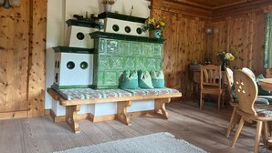 A wooden-paneled room with a green and white chest of drawers, a bench, and a dining area with chairs and a table.