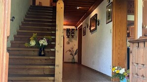 A wooden staircase leading to a second floor, a hallway with tiled flooring, and a door on the right.