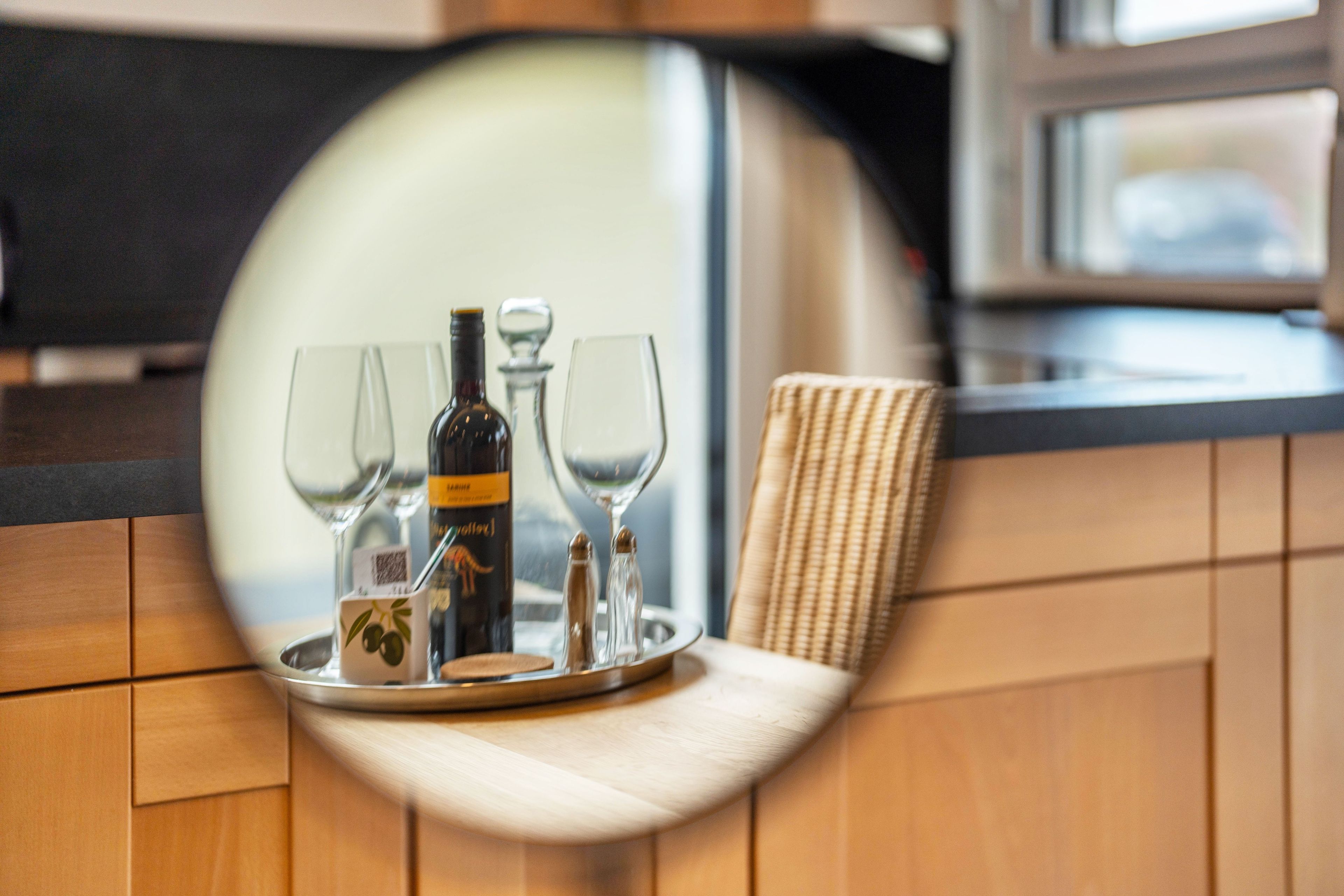 A tray with a bottle and glasses on a wooden counter.