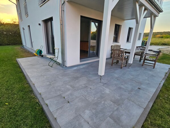 Une maison moderne dotée d’un patio, d’un coin repas et d’un garage.