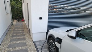 Een witte auto geparkeerd in een smalle oprit, met een garage deur op de achtergrond.