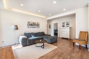 Un salon moderne avec un canapé gris, une table basse ronde et un fauteuil en osier.