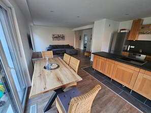 Una cocina moderna con armarios de madera, una mesa de comedor con sillas y una sala de estar con sofá y una mesa baja.