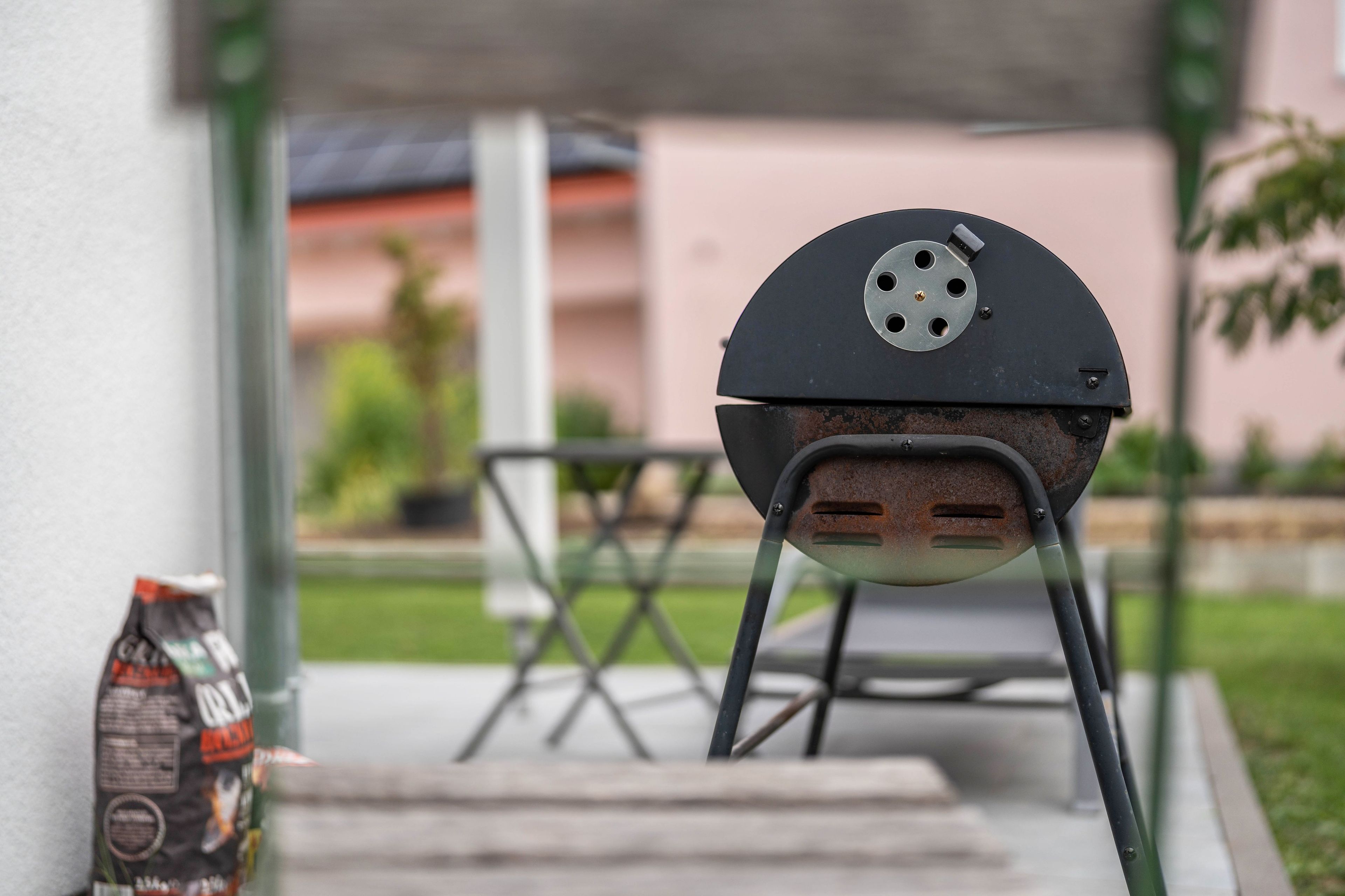 Un barbecue doté d’une plaque en métal et d’une poignée, placé sur un support dans un espace extérieur.