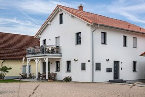 Een gebouw met twee verdiepingen, voorzien van een balkon, een deur en een raam.