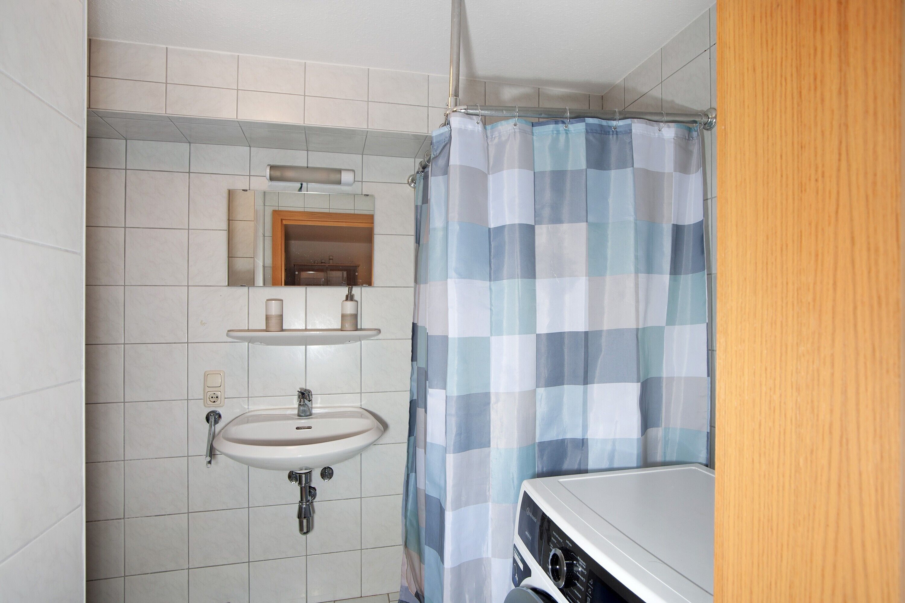 Un baño con lavamanos, espejo y cortina de ducha.