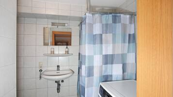 Un baño con lavamanos, espejo y cortina de ducha.