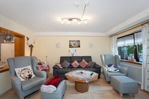 Ein Wohnzimmer mit einer Couch, zwei Sesseln, einem Couchtisch und einem Kamin.