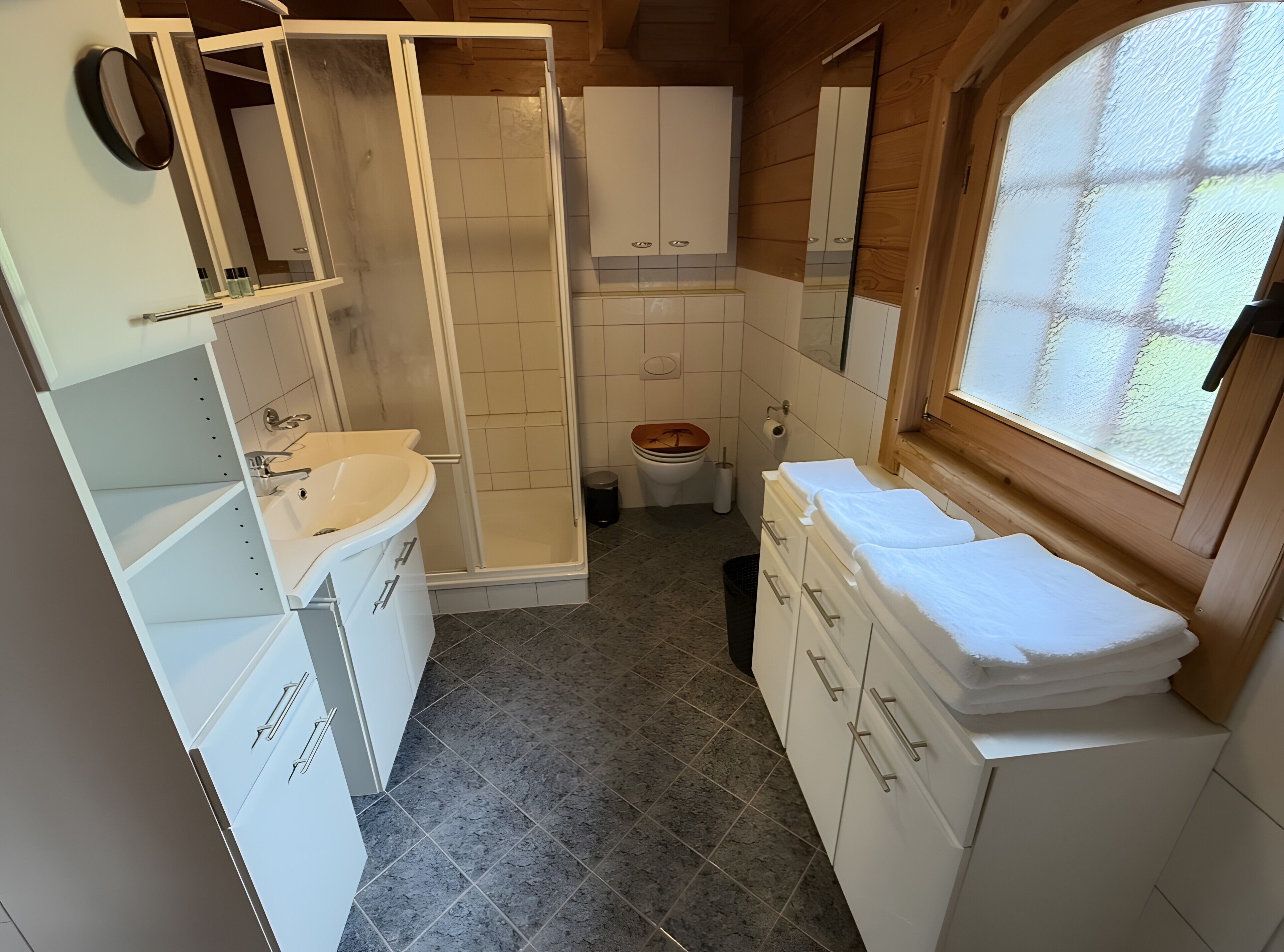 A compact bathroom with a shower, toilet, sink, and vanity.