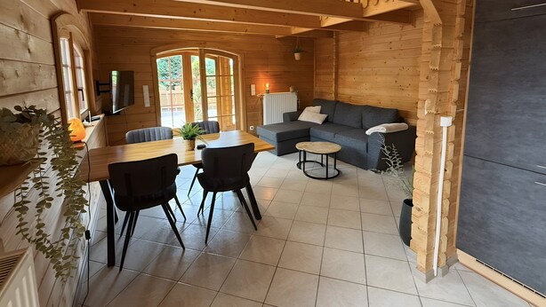 A wooden interior with a dining area, sofa, and a large window. - Holiday Home 'Idylle Ferienhaus Ems' with Lake View, Wi-Fi and Air Conditioning (Walchum)