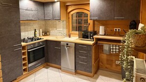 A modern kitchen with dark cabinets, stainless steel appliances, and wooden accents. - Holiday Home 'Idylle Ferienhaus Ems' with Lake View, Wi-Fi and Air Conditioning (Walchum)