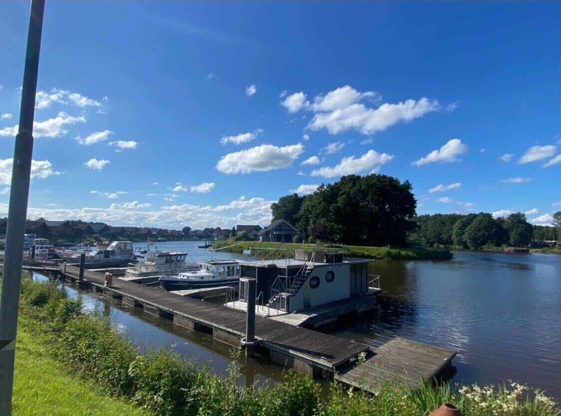 A dock with boats, a small building, and a tree-lined riverbank.