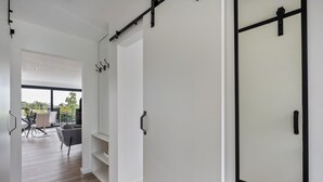Un interior moderno con una puerta corredera, un comedor con mesa y sillas, y vistas a través de un ventanal grande.