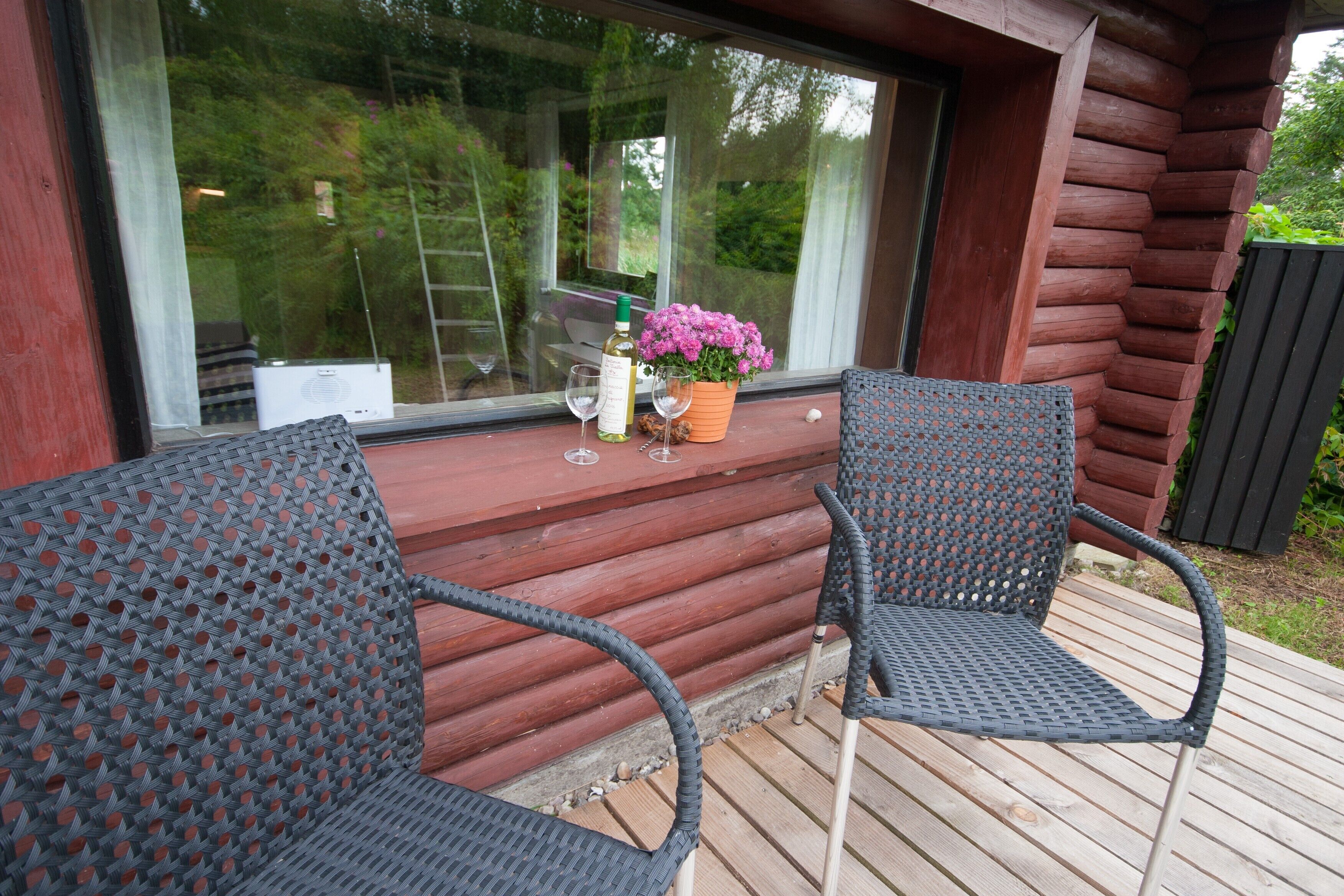 Eine Holzterrasse mit zwei Korbstühlen, einer Weinflasche und einem Blumentopf.