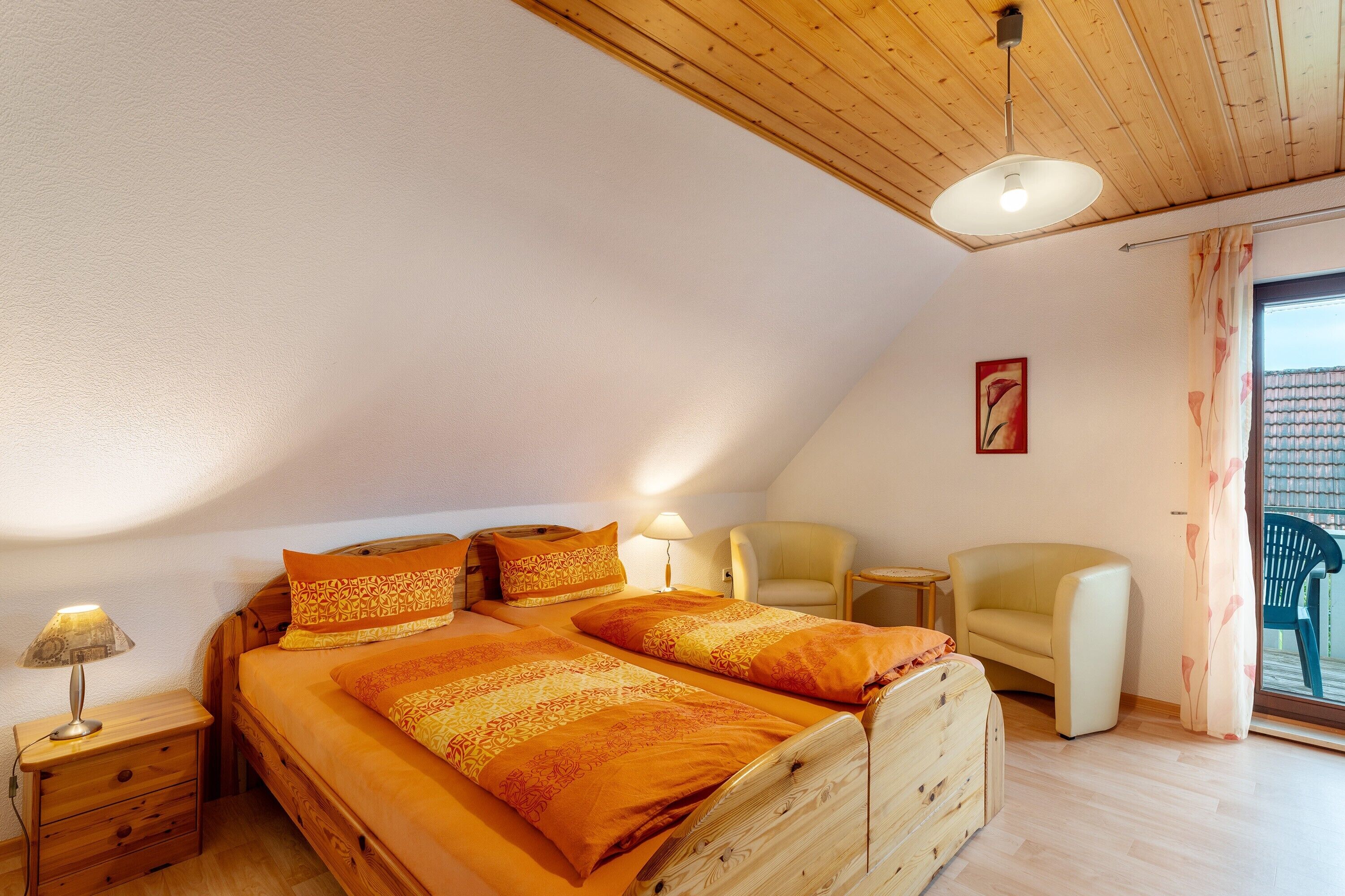 A bedroom with two beds, a chair, a nightstand, and a window with curtains.