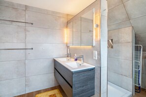 Een moderne badkamer met een grote spiegel, een wastafel en een douchehoek.