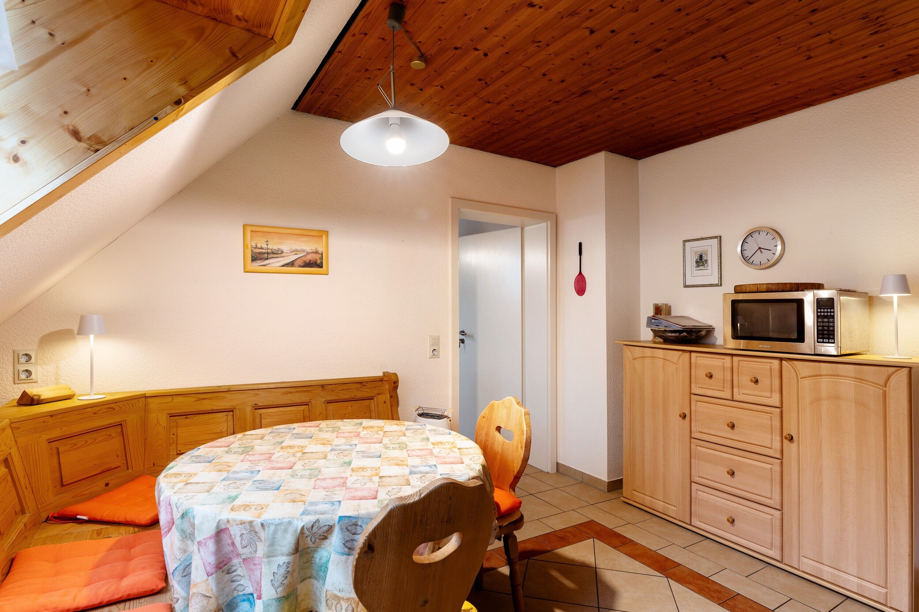 A cozy kitchen with wooden cabinets, a microwave, and a dining area with a table and chairs.