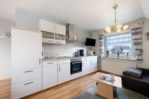 Une cuisine moderne avec des meubles blancs, un four à micro-ondes et une machine à café.