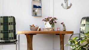 A wooden table with a vase of flowers, a ship-shaped ornament, and a small plant. - Apartment 'Haus Sünnschien' with Shared Terrace, Shared Garden and Wi-Fi (Nordstrand)